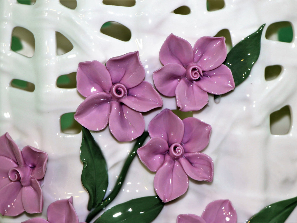 Wide mouth porcelain vase with realistic purple flowers.