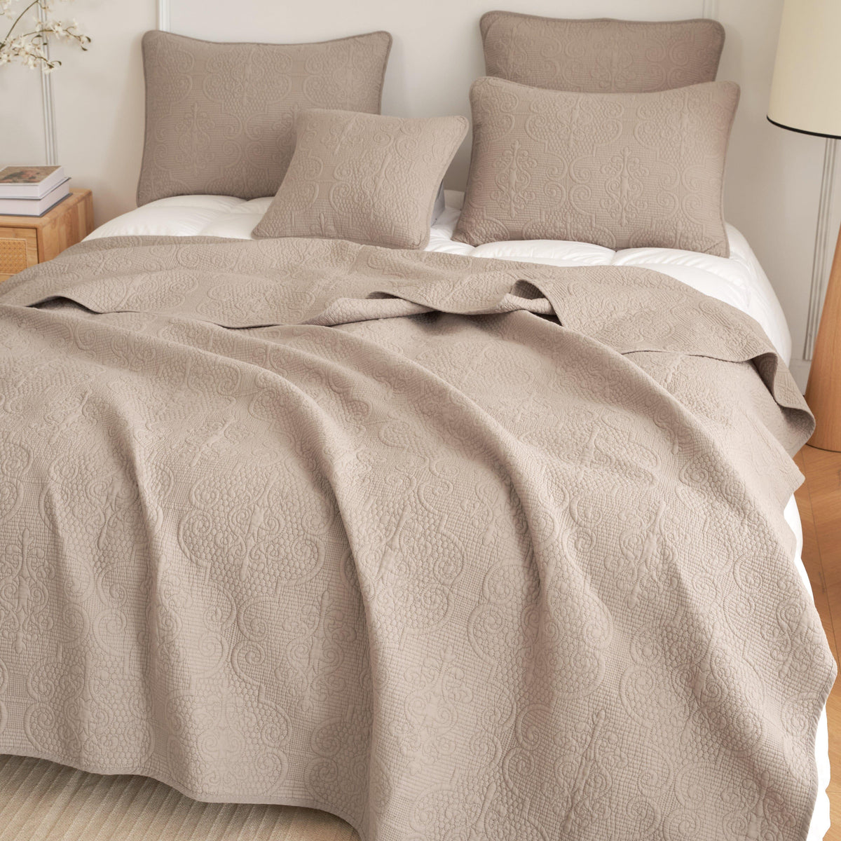 Taupe beige matelasse cotton quilted bedspread set draped on a bed.