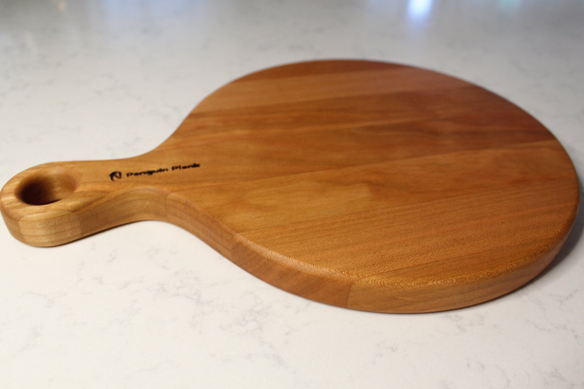 Round cherry wood cheese board with a smooth finish, perfect for charcuterie.