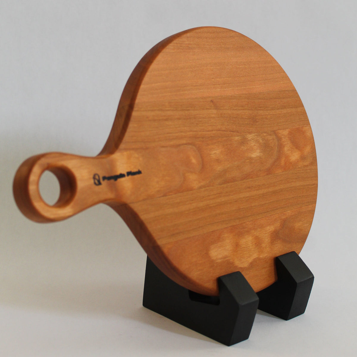 Round cherry wood cheese board serving platter with charcuterie and appetizers.