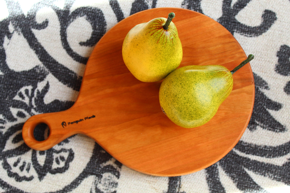 Round cherry wood cheese board with a natural edge, perfect for charcuterie.