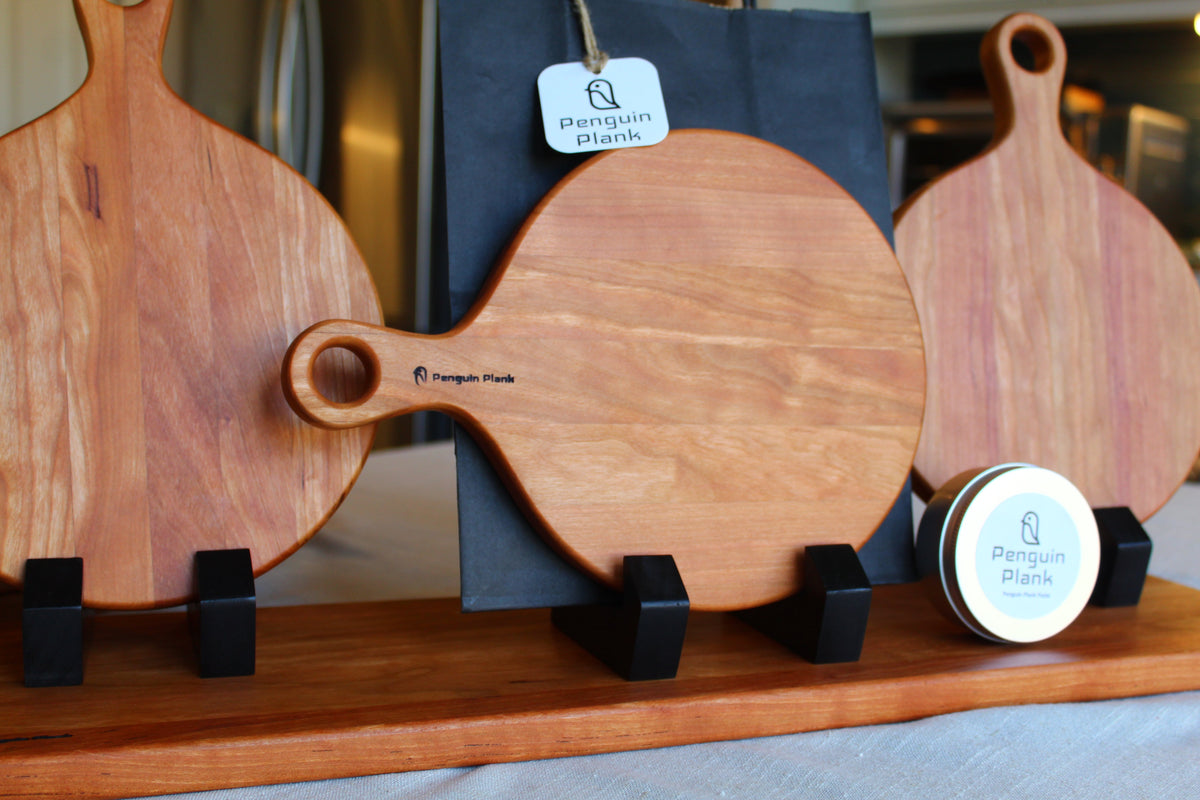 Round cherry wood cheese board with charcuterie and appetizers displayed.