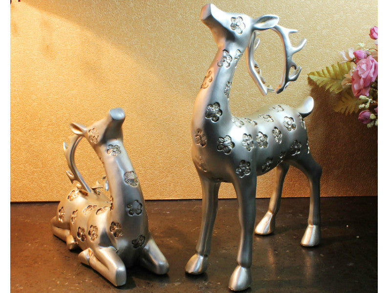 Elegant silver deer sculptures with antlers, sold as a pair.