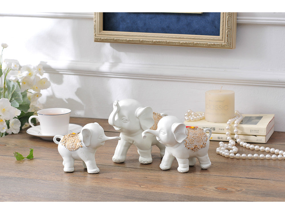 White resin sculpture of three elephants, a family of two adults and one baby.