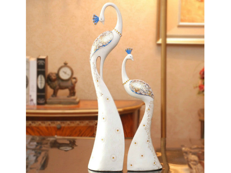 Two hand-painted white and blue peacock sculptures for table decor.