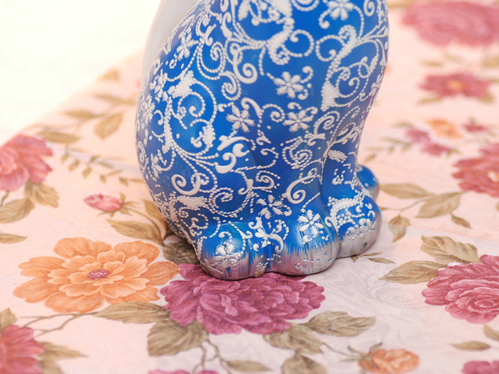 Two hand-painted blue resin cat sculptures, smiling, as table decor.