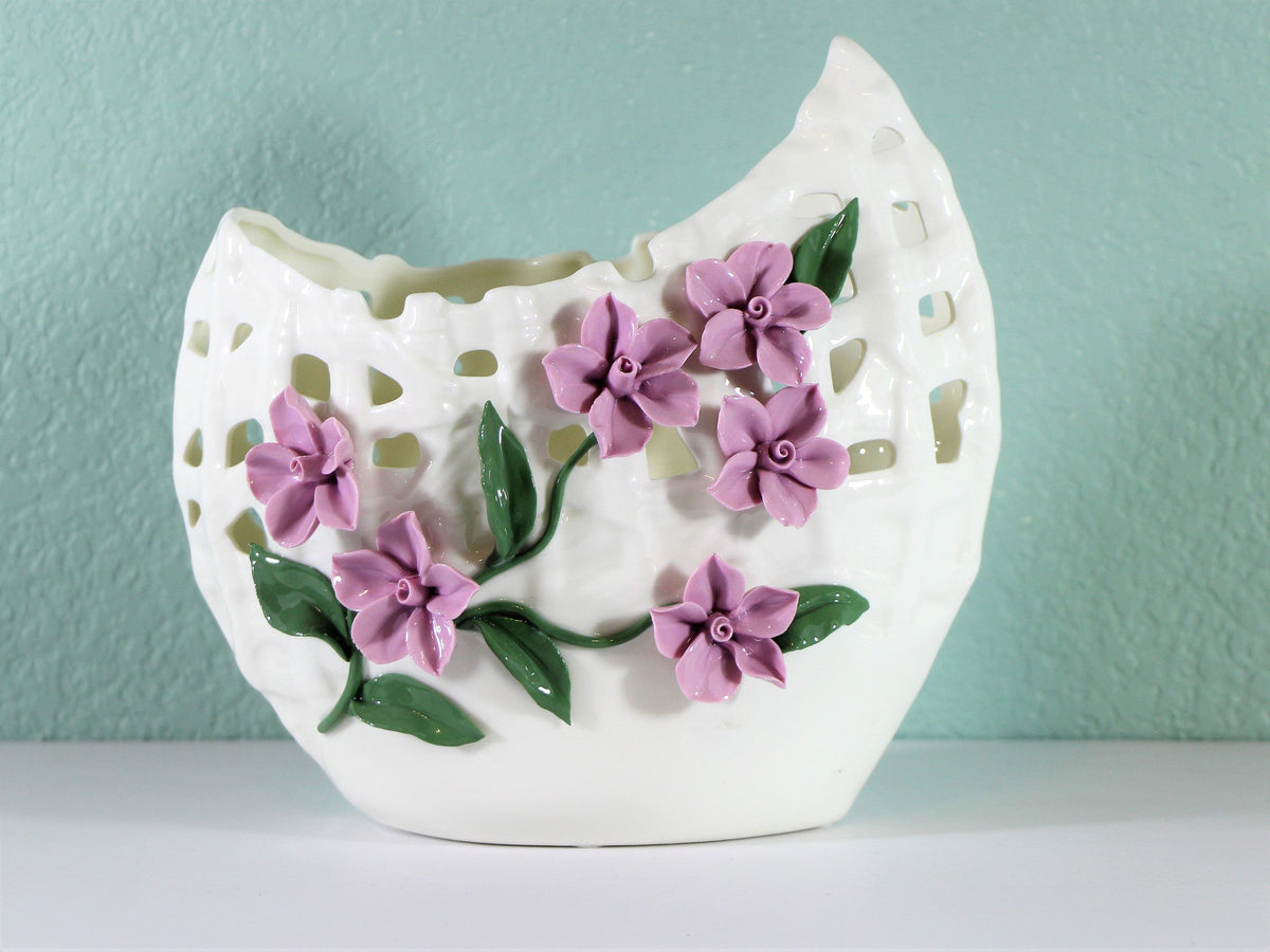 Wide mouth porcelain vase with delicately pinched purple flowers.