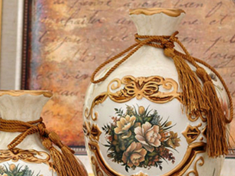 Three light brown ceramic vases with gold rims and tassels.