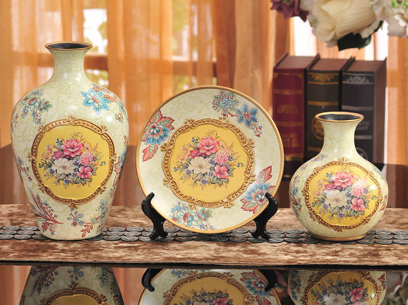 Three vintage yellow ceramic vases with gold bands and floral designs.