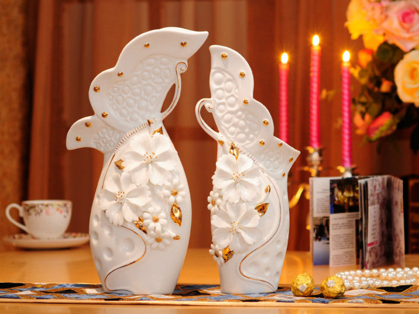 White porcelain vase set with pinched flowers and gold leaves.