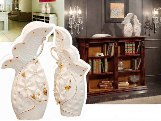 White porcelain vase set with pinched flowers and gold leaves.