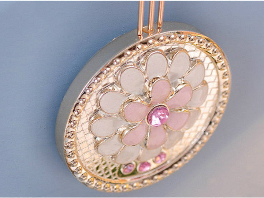 Metallic gold pendulum wall clock with pink stone accents.