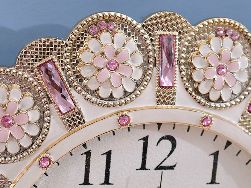 Metallic gold pendulum wall clock with pink stone accents.