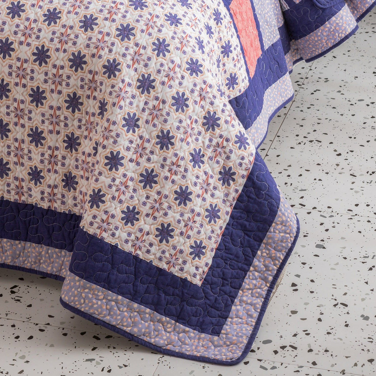Peachy pink plum purple floral patchwork quilted bedspread set with decorative stitching.