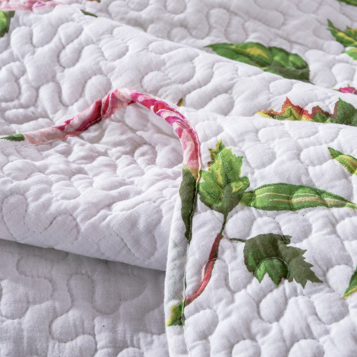 Pink floral quilted bedspread set with roses and scalloped edges.