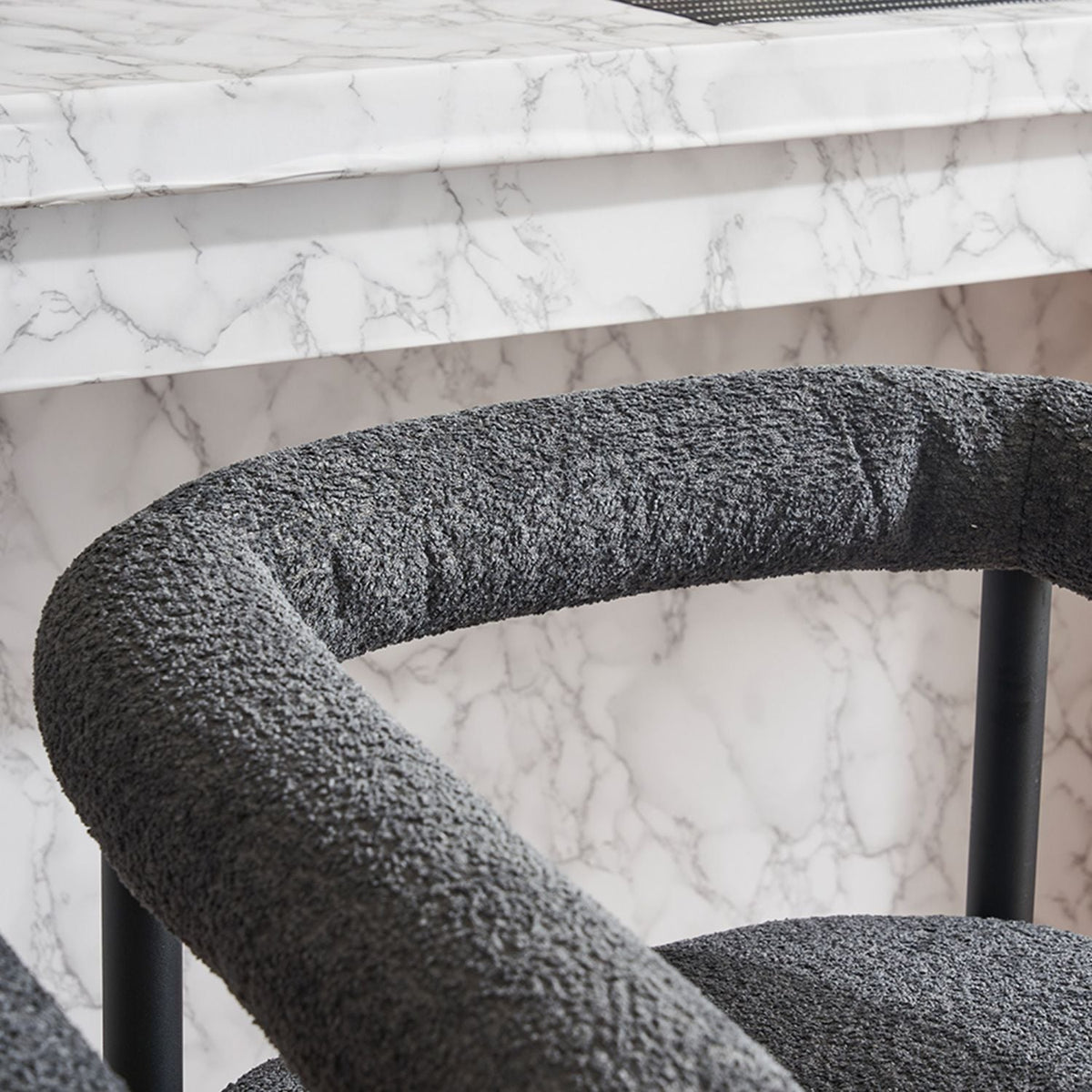 Two cream boucle upholstered bar stools with black legs.
