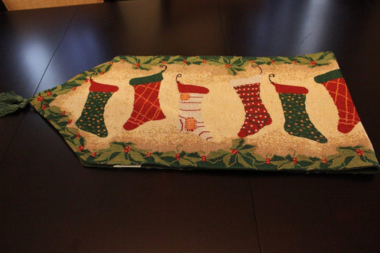 Christmas table runner with stockings and fireplace decor wall hanging.